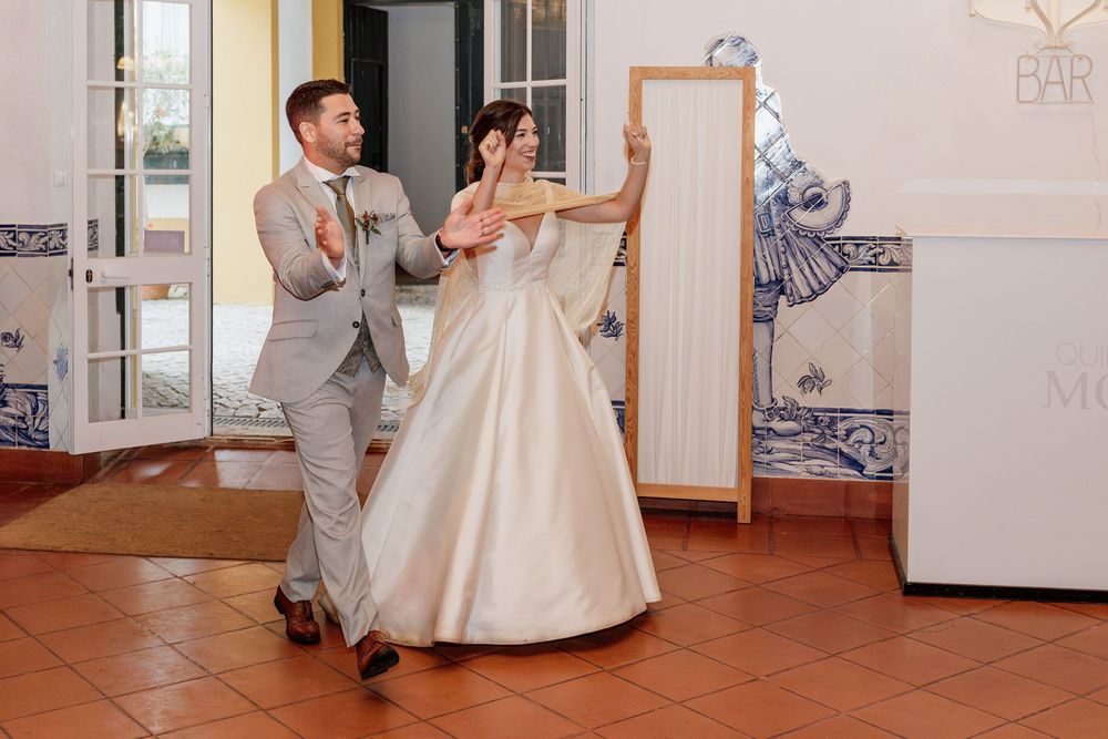 Bride in white ball gown and groom in gray suit share first dance at elegant wedding reception venue.