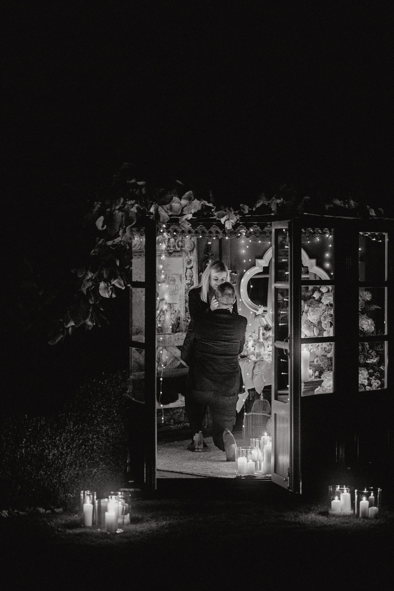 Black and white photo of candle-lit doorway with vines creating a romantic nighttime atmosphere.