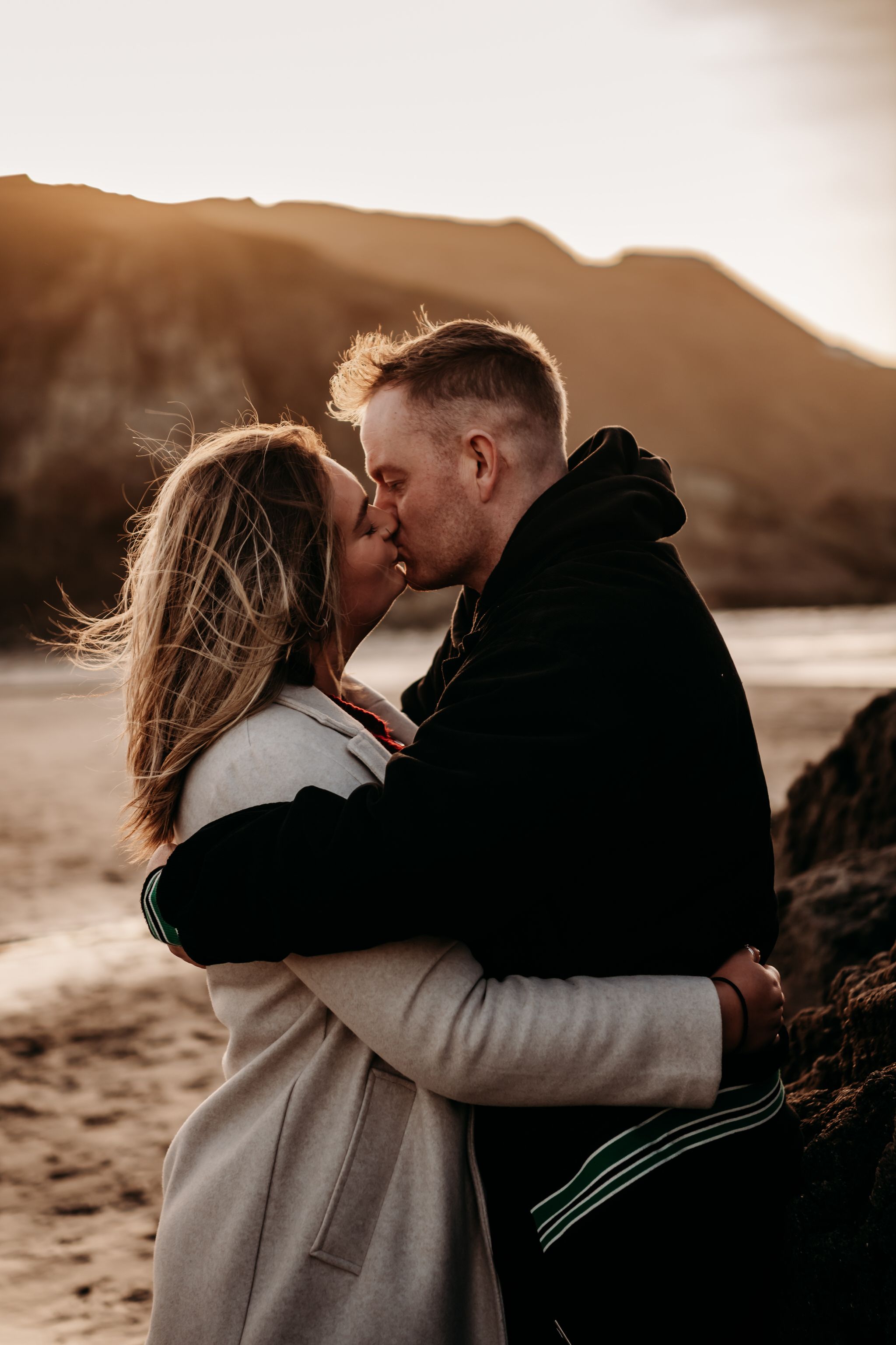A romantic couple shares tender moments on a beach at sunset in a series of intimate photographs.