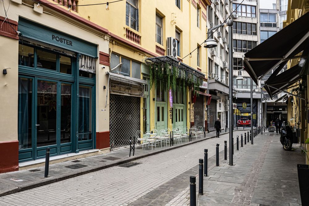 Empty urban street with historic buildings and storefronts on both sides during daytime.