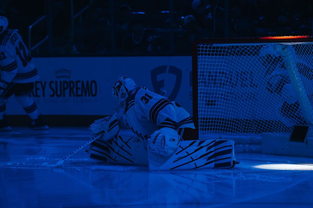 A hockey goalie crouches in front of the net during a dramatic blue-lit pre-game introduction sequence.