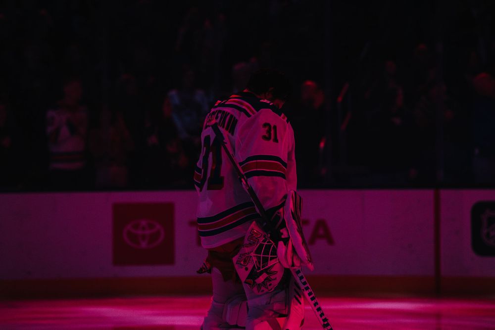 Hockey player in red jersey makes a diving save attempt during an intense game on ice.
