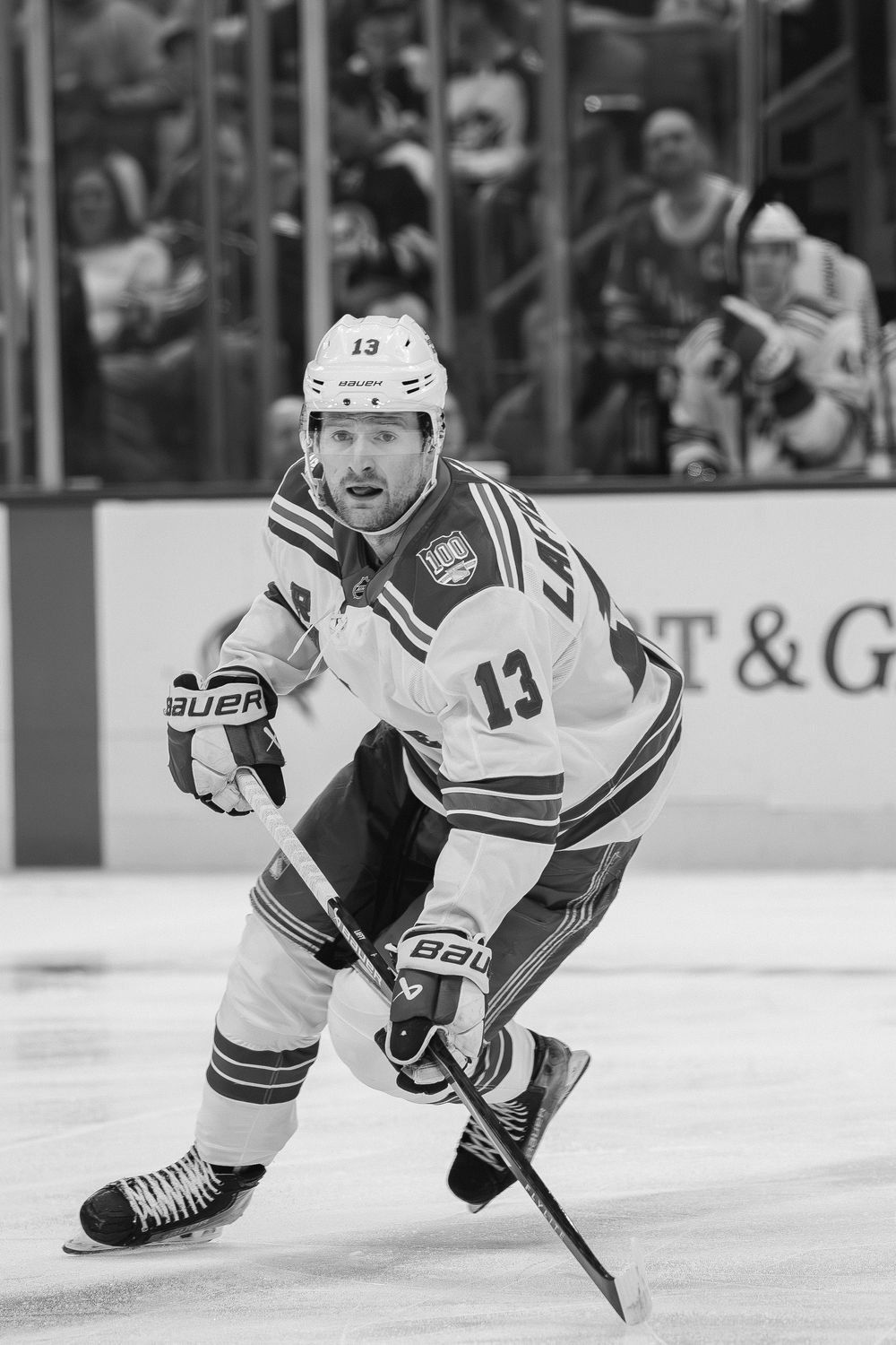 A hockey player in a white jersey with number 13 skates on ice during a professional game in black and white.