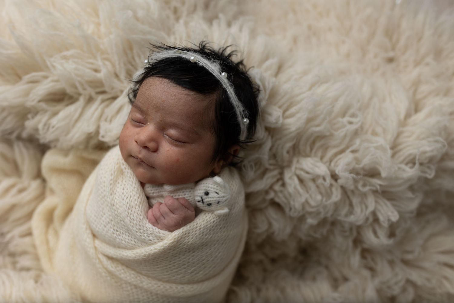 Unedited picture of baby girl against a soft cream fur rug, captured by Charlottesville family, maternity, and newborn photographer.