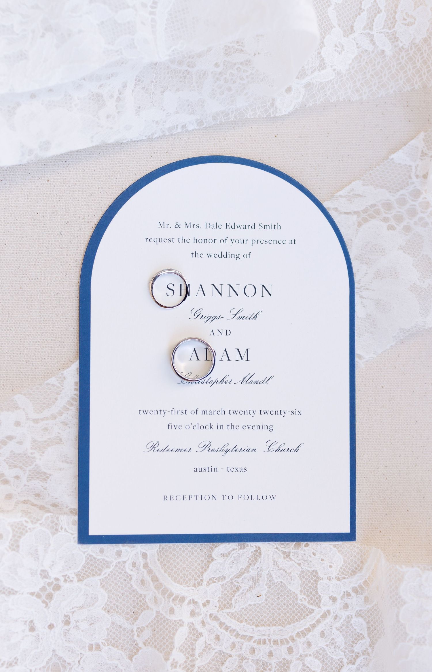 Classic arched wedding invitation with navy blue border and elegant typography on white lace background.
