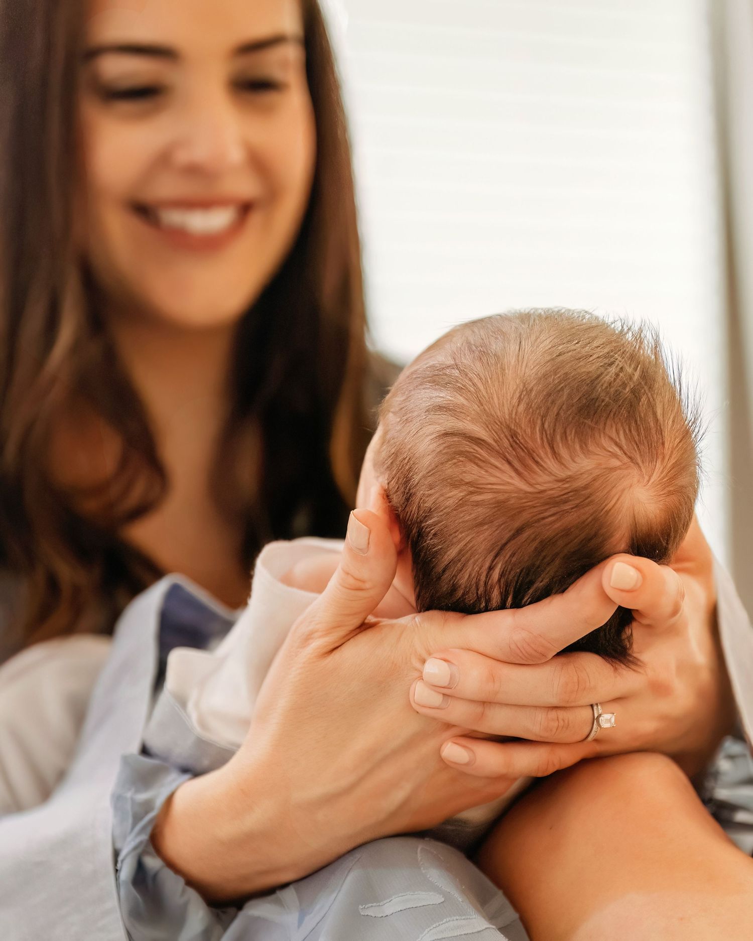 A newborn baby being gently cradled and supported in loving hands in Southlake, TX.