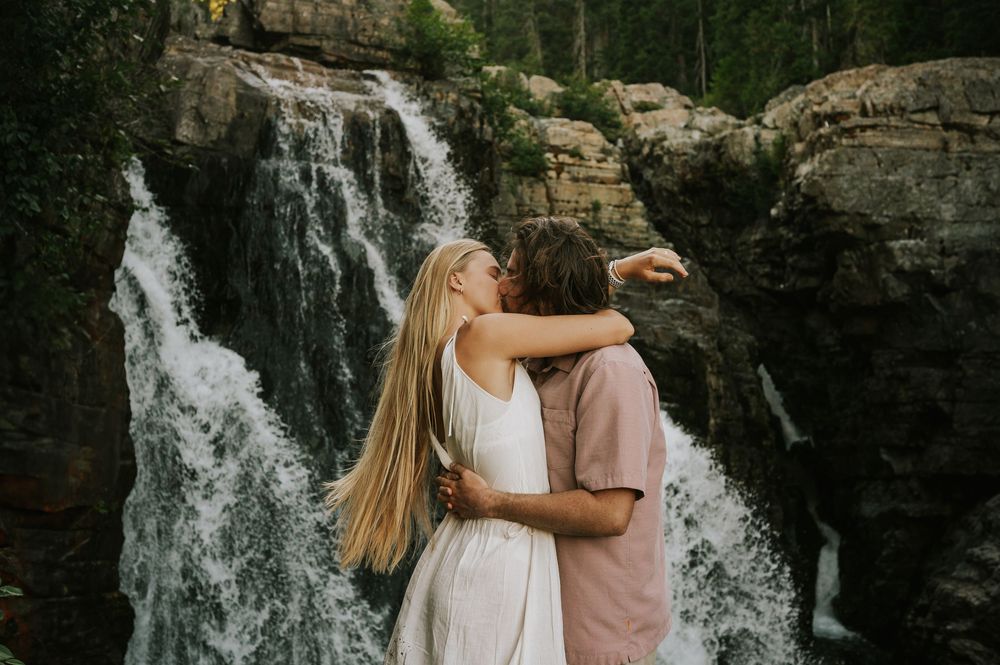 Couple adventure photoshoot session Vancouver island taken by professional photographer of couple kissing by lower Myra Waterfalls