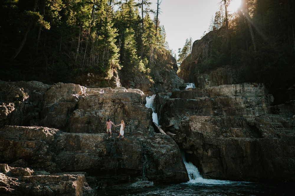 Couple adventure photoshoot session at Myra Falls on Vancouver island taken by professional photographer of couple walking by waterfall