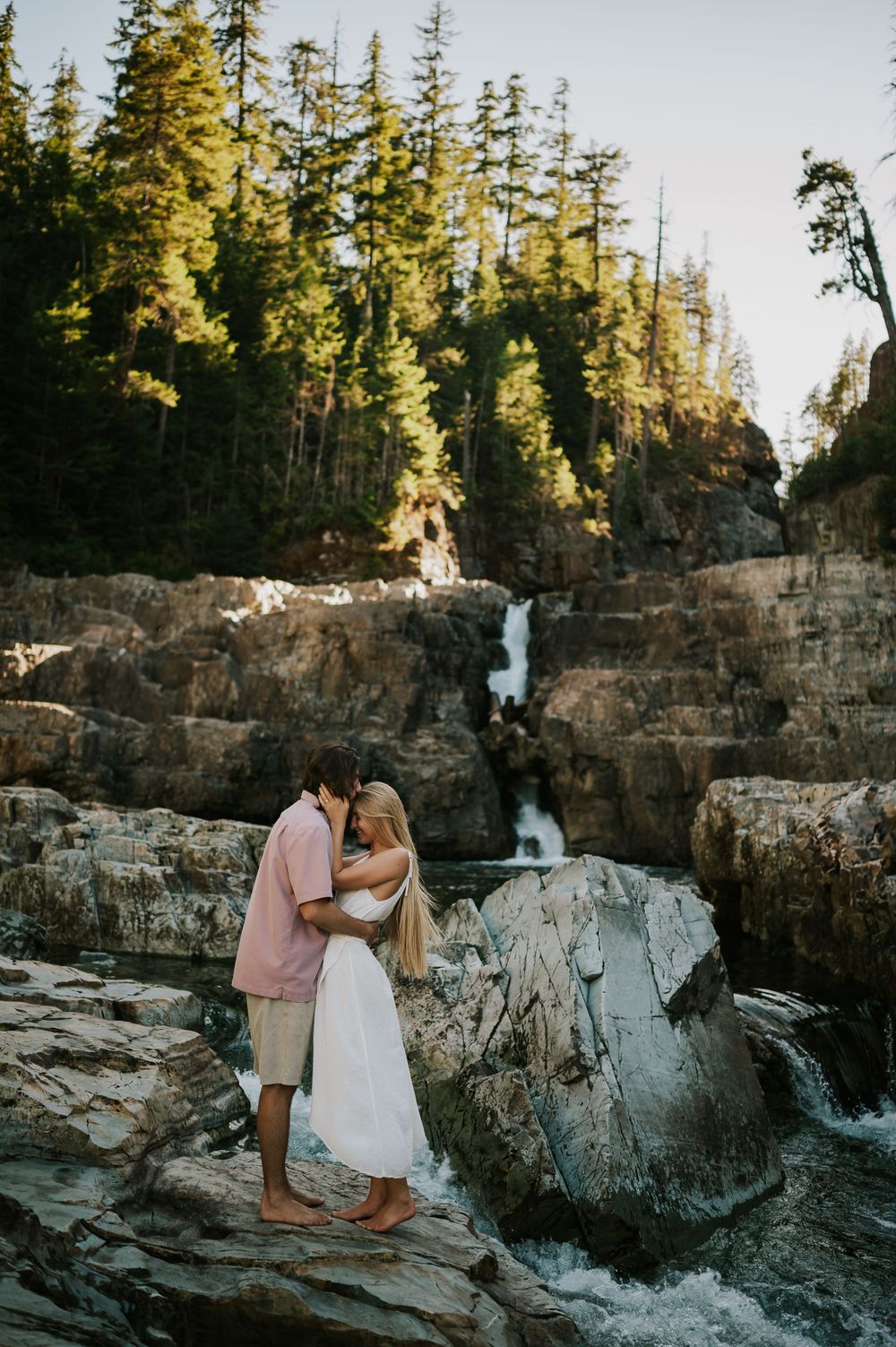 Couple adventure photoshoot session at Myra Falls on Vancouver island taken by professional photographer of couple embracing by waterfall