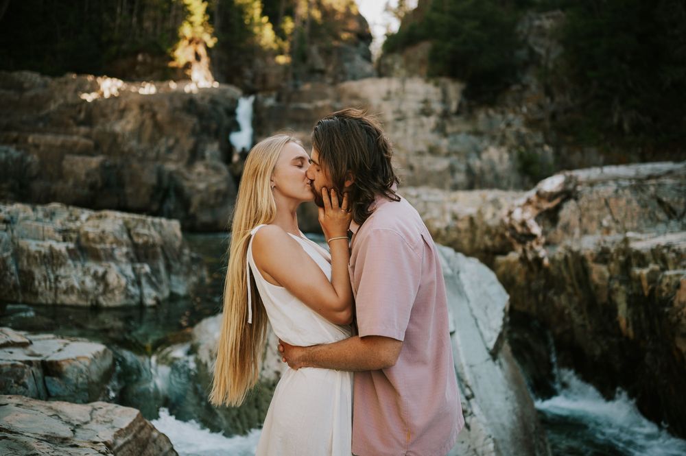 Couple adventure photoshoot session at Myra Falls on Vancouver island taken by professional photographer of couple kissing by waterfall