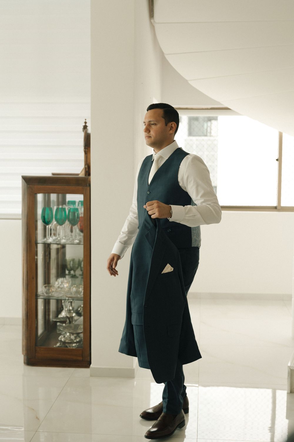A series of photos showing someone in a dark vest and white shirt walking through a minimalist interior space.