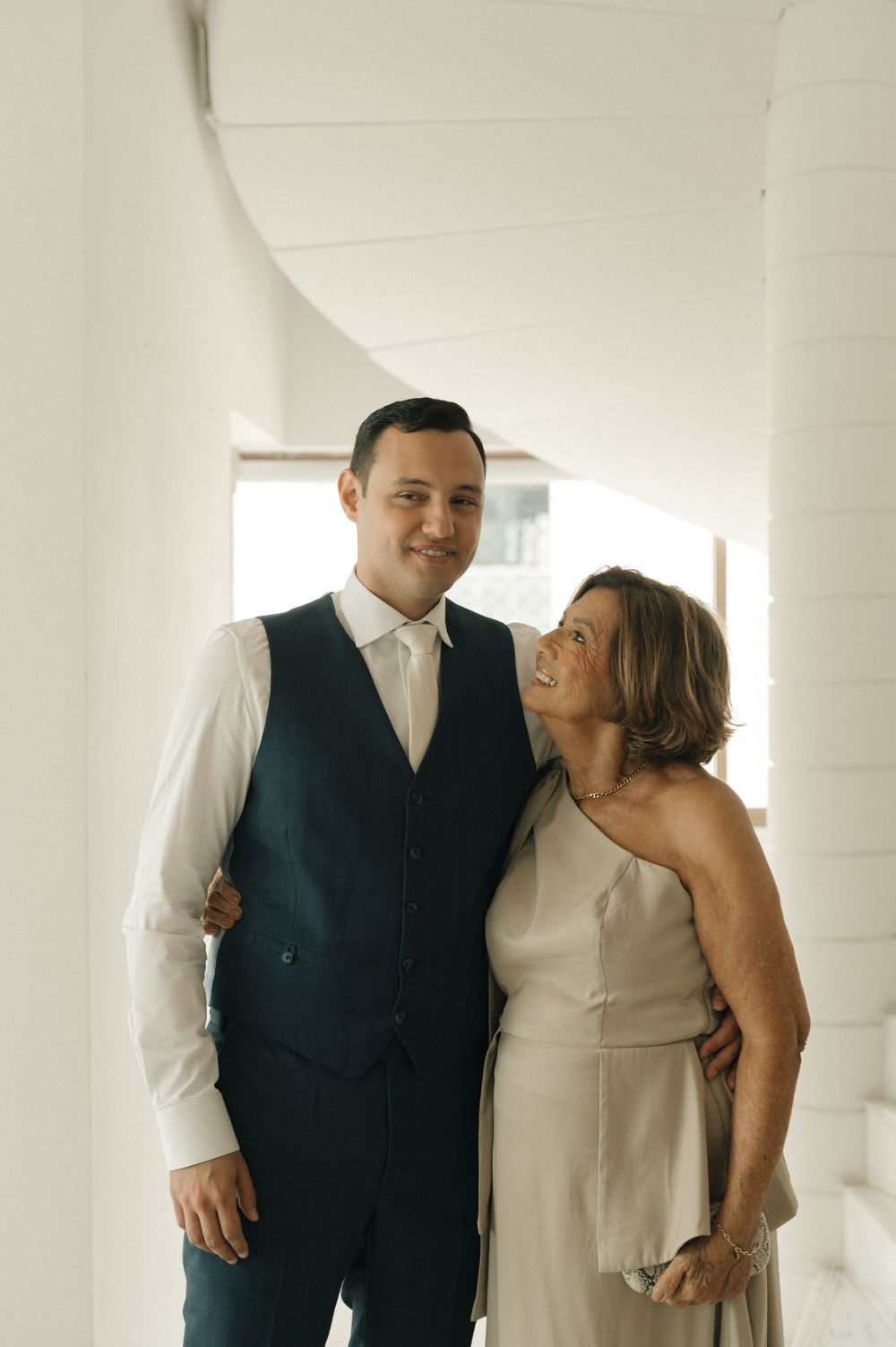 A couple shares a joyful moment together in a bright white interior space.