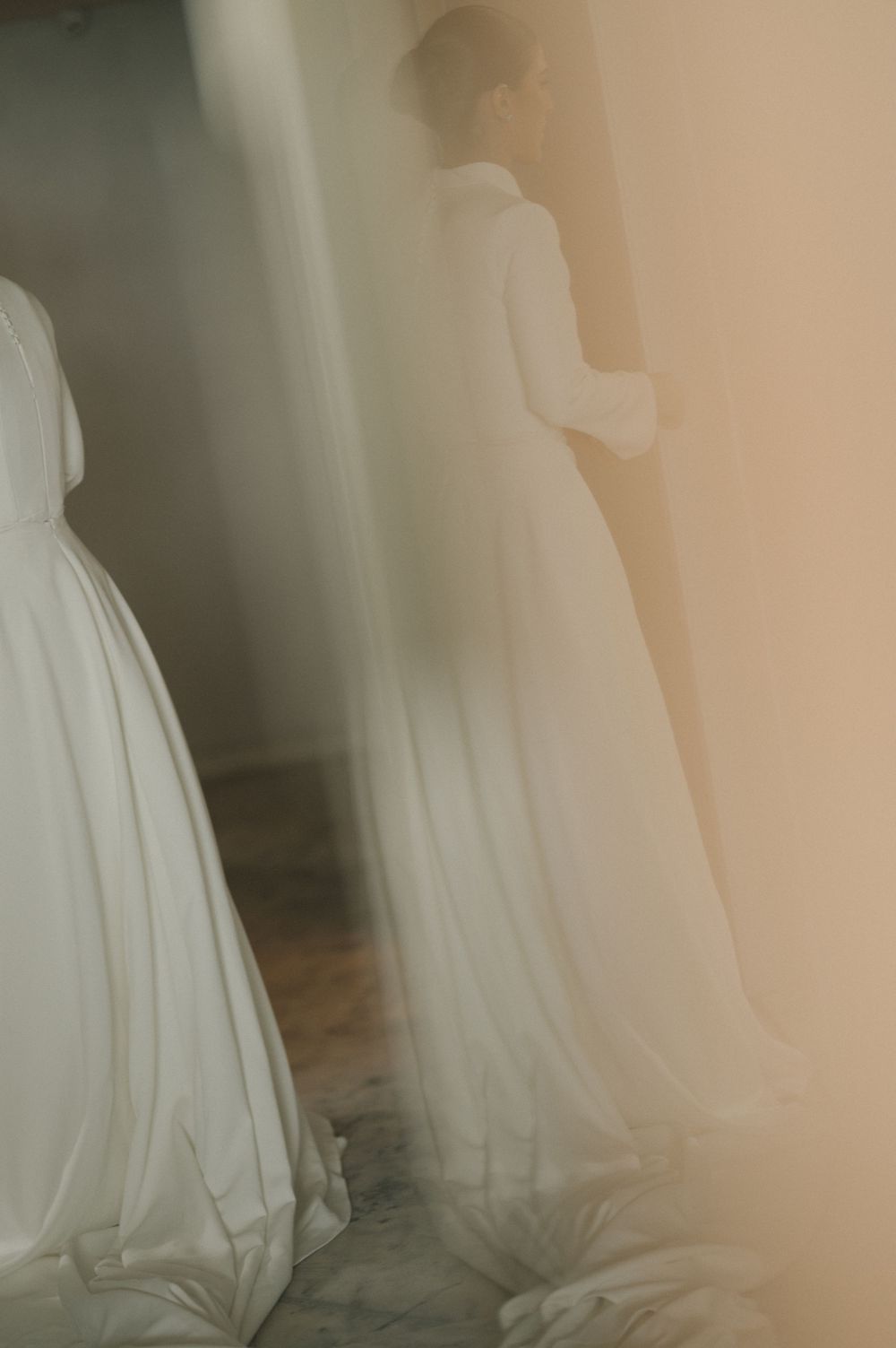 Multiple white wedding dresses hanging in a soft, ethereal light creating a dreamy atmosphere.