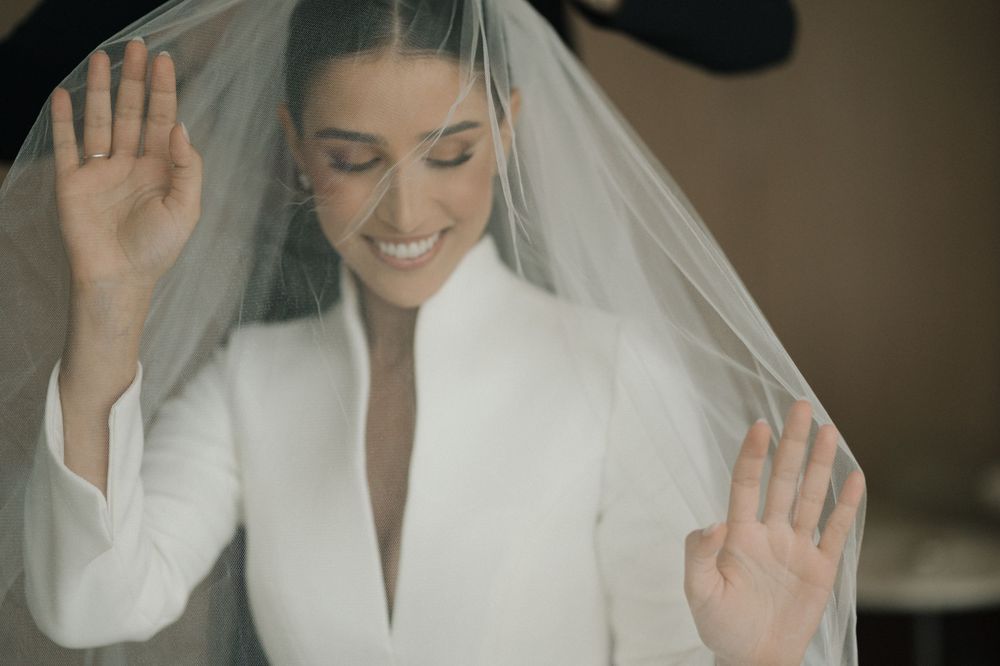 A bride in a white dress and veil smiles joyfully during her wedding celebration.