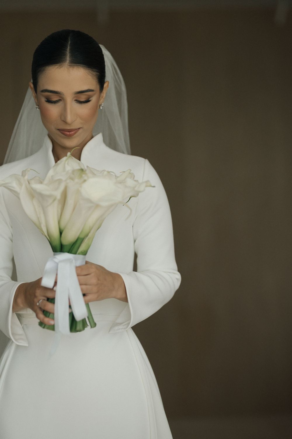 Close-up shots of a bride in white holding a classic calla lily bouquet.