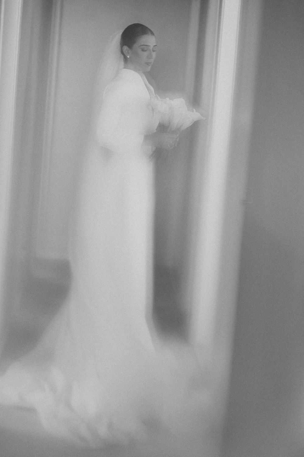 Ethereal black and white wedding photos showing blurred movement and dancing in a softly lit interior space.