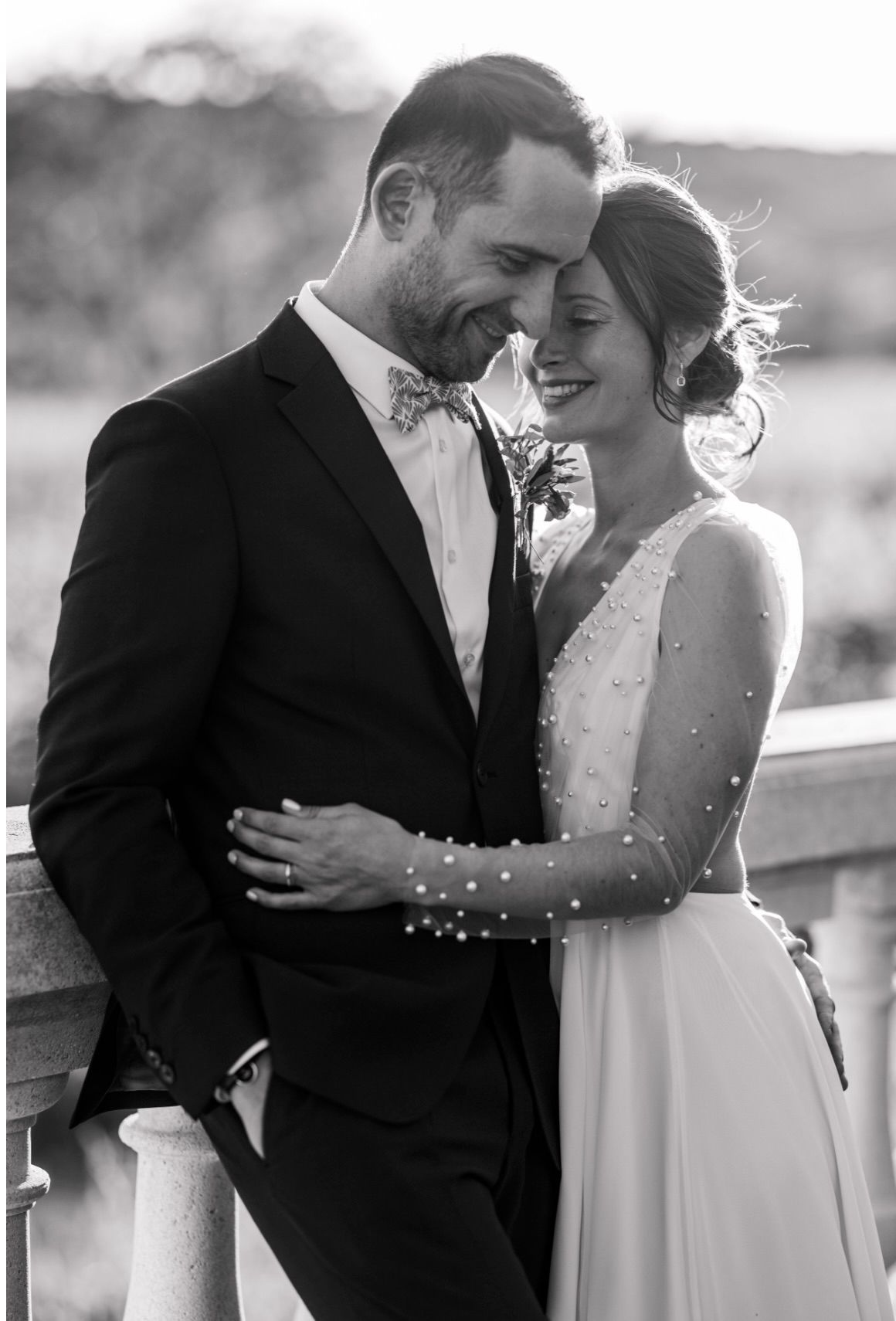 Silhouetted couple shares romantic sunset kisses in wedding attire with veil flowing in golden light.