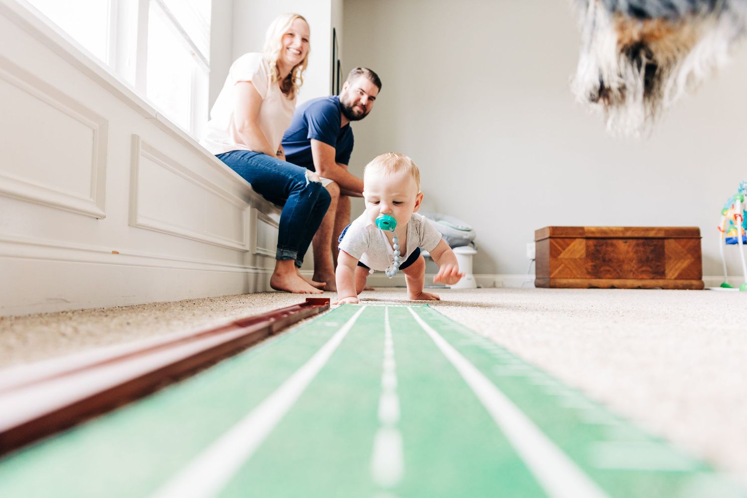 A photo showing a child playing with a putting set on a green mat at home.