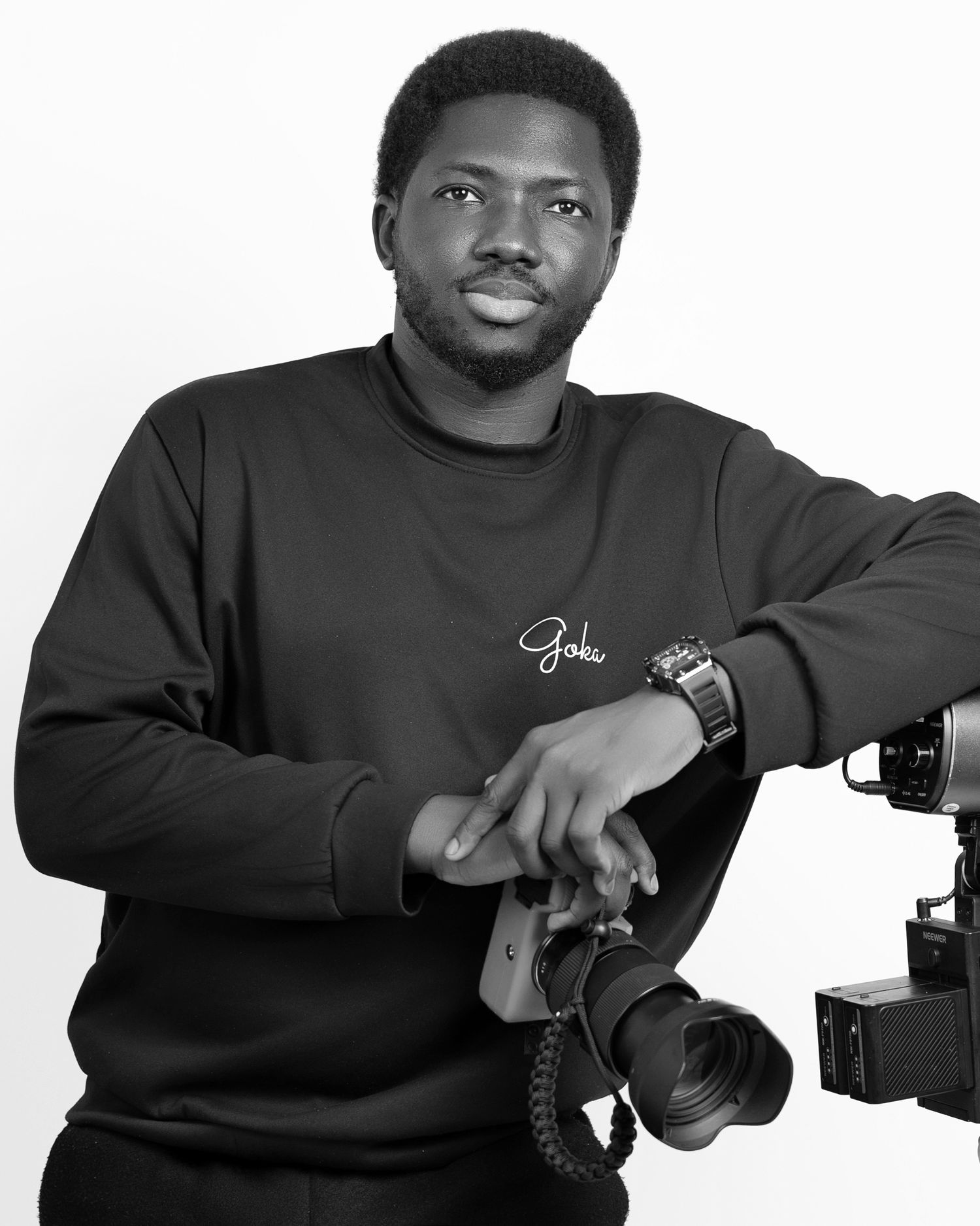 Black and white portrait of a young man in a sweatshirt holding a professional camera and gimbal stabilizer.