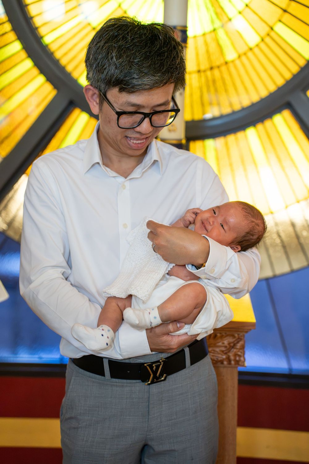 Tender moment of a father looking at his baby by the holy water font inside a Tempe Catholic church, by N&D Media Production.