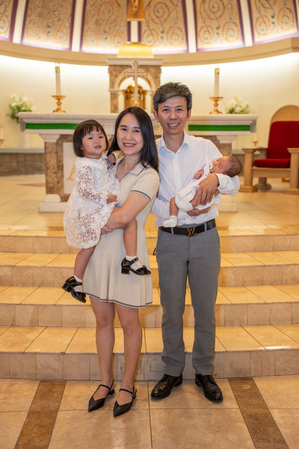 Family portrait inside a Tempe Catholic church following an infant baptism, photographed by N&D Media Production.