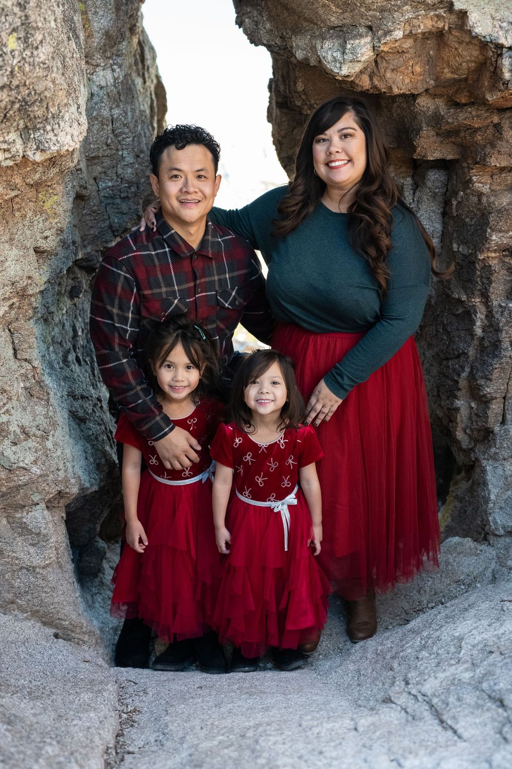 Smiling family of four posing inside a scenic rock cove on Mount Lemmon near Tucson, Arizona, by N&D Media Production.
