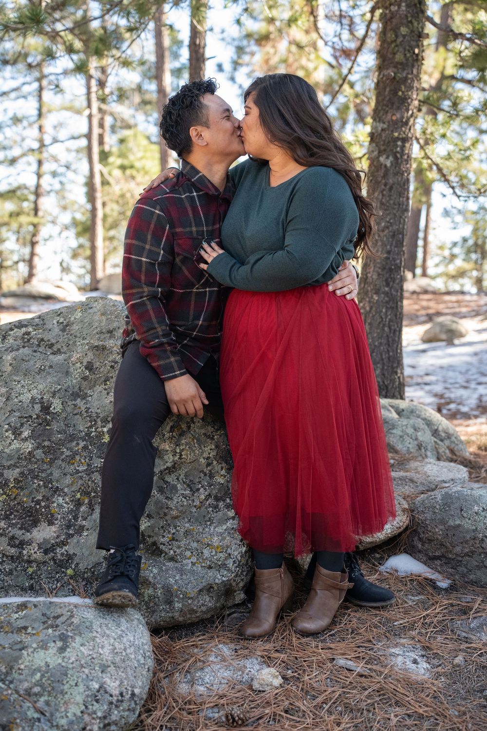 Couple in festive holiday colors embracing and kissing during a winter session on Mount Lemmon, by N&D Media Production.