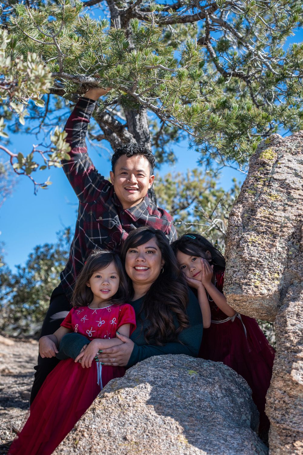 Family of four in holiday colors posing on a rocky outcrop during winter on Mount Lemmon in Tucson, by N&D Media Production.