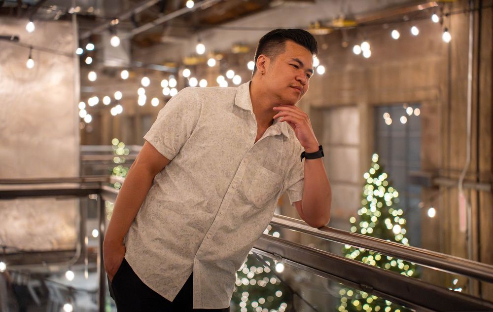 Pensive portrait of a man resting on a railing under string lights during a summer session in Springville, UT, by N&D Media.