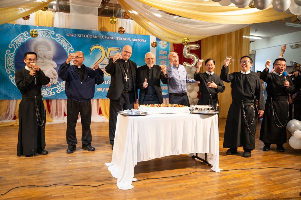 Documentary photo of bishops and priests toasting behind a cake at the Our Lady of La Vang 25th anniversary, by N&D Media.