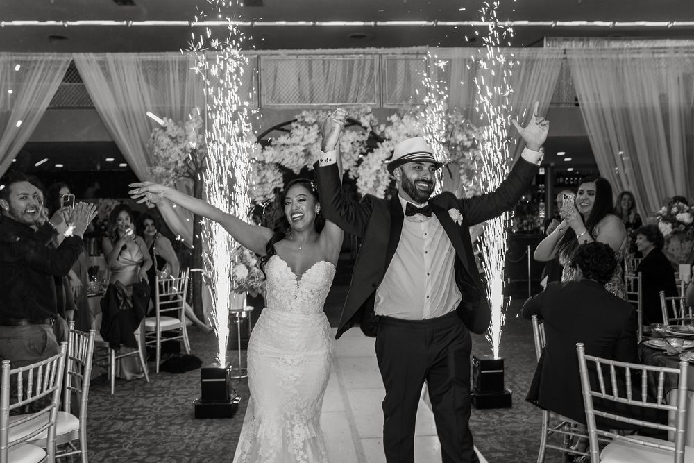 A bride and groom enter their wedding reception with sparklers behind them at Babylon Palace.
