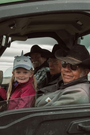 A family rides together in a car with cowboy hats and smiles during a ranch outing.