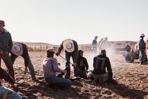 Cowboys rest in the dusty ground during a cattle roundup.
