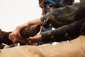Close-up of hands working on repairing or adjusting mechanical equipment with a leather surface visible beneath.