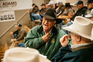 Students wearing green jackets take notes during a classroom lecture at a university.