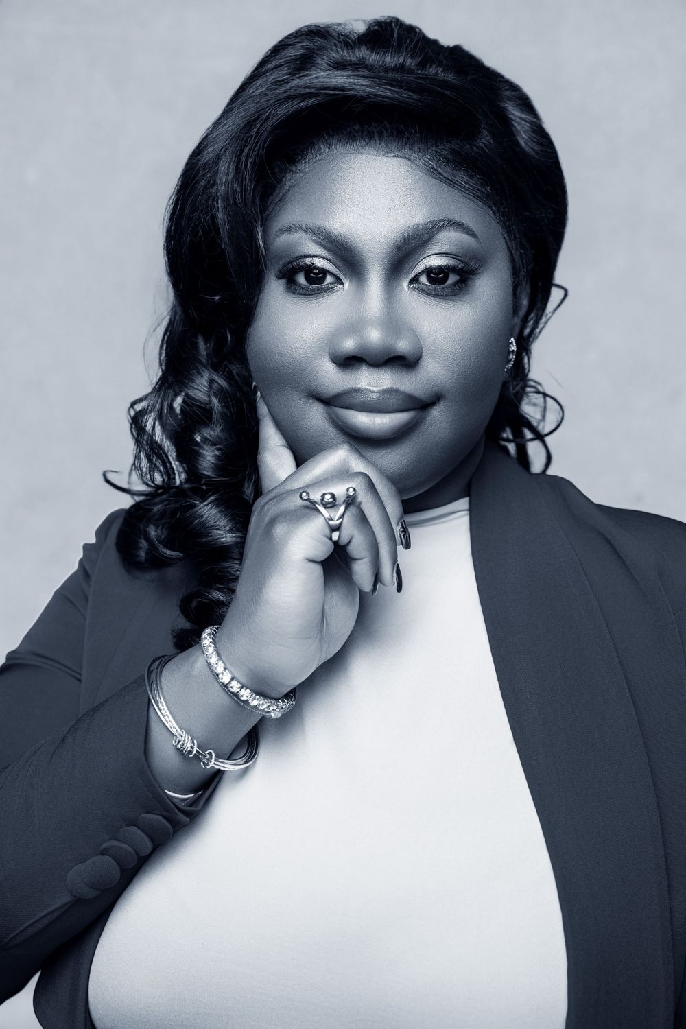 Professional black and white portrait of a confident woman in blazer with jewelry, posing thoughtfully.