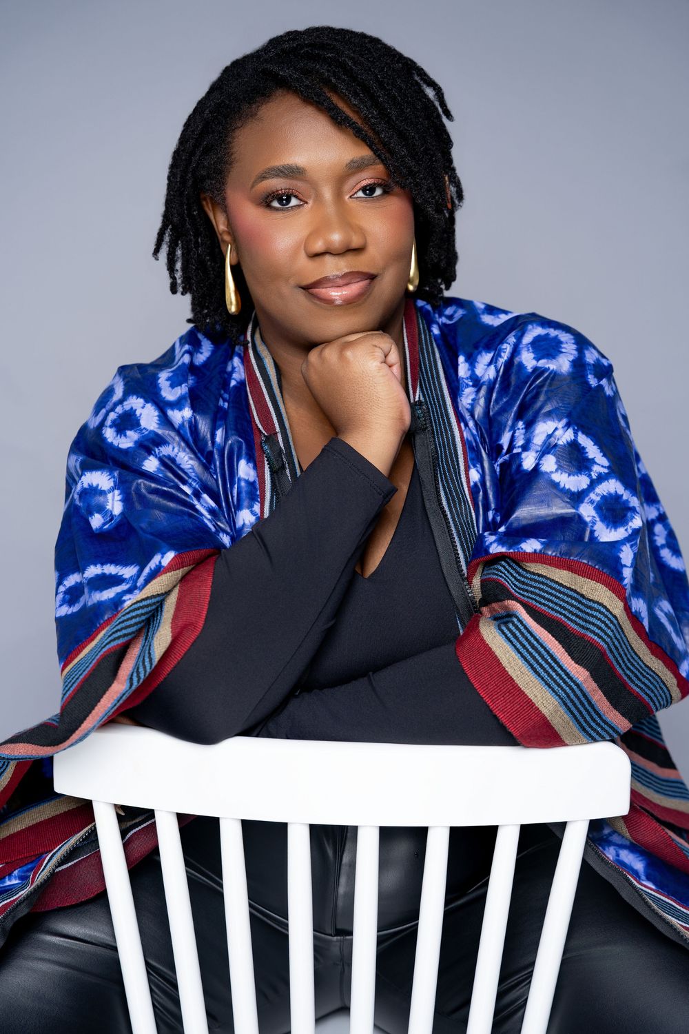 A person poses in a vibrant blue tie-dye jacket and black top against a gray background in a photo series.