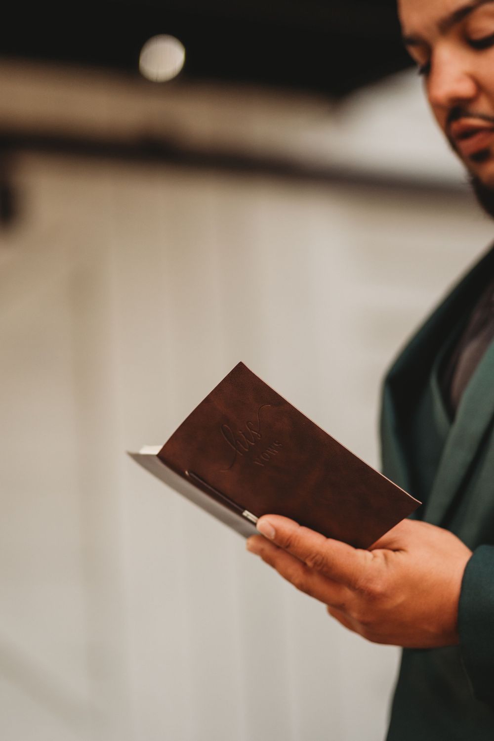 Close-up shot of hands holding a brown leather book against white background.