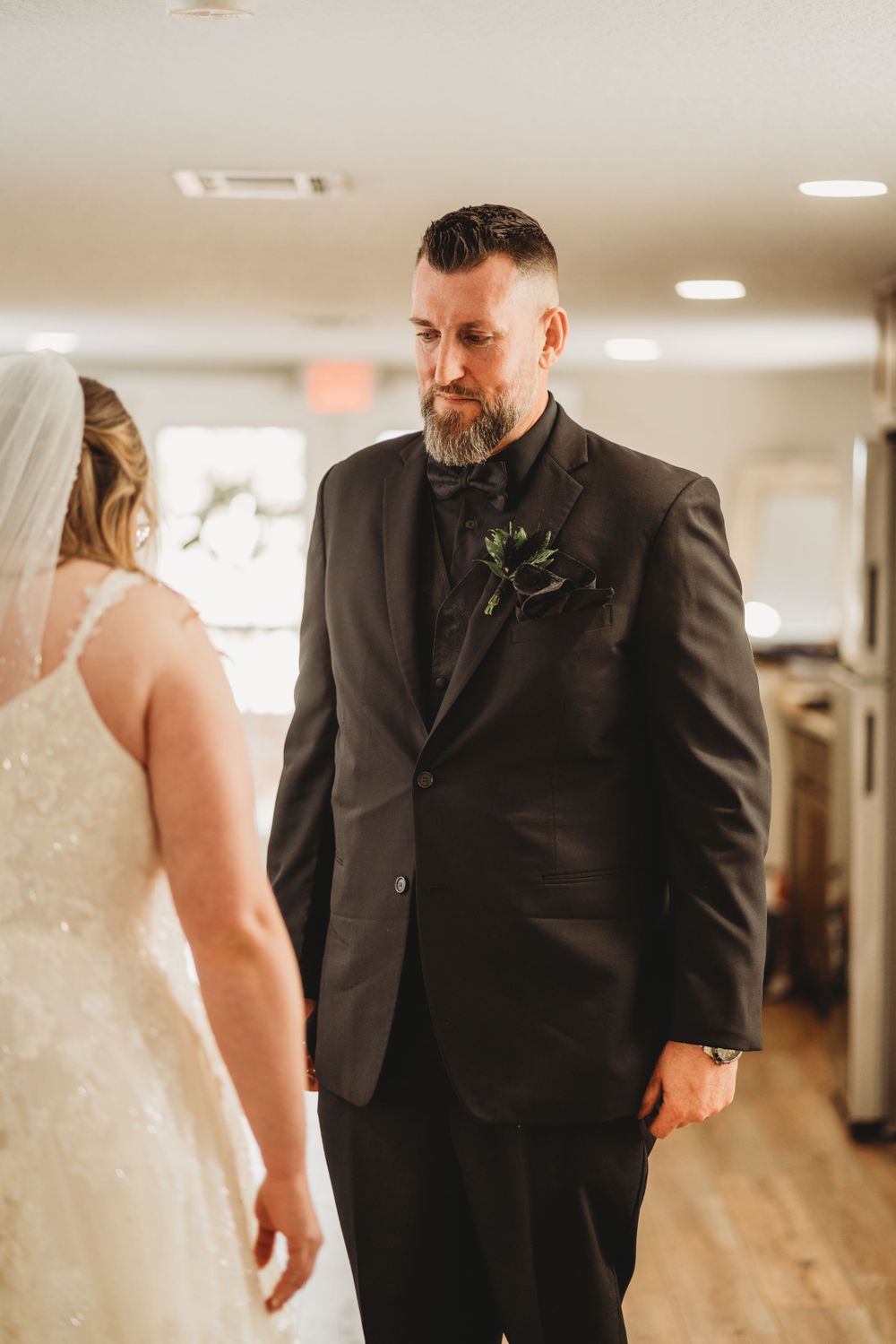 Wedding moment captured in indoor hallway setting with wooden floors.