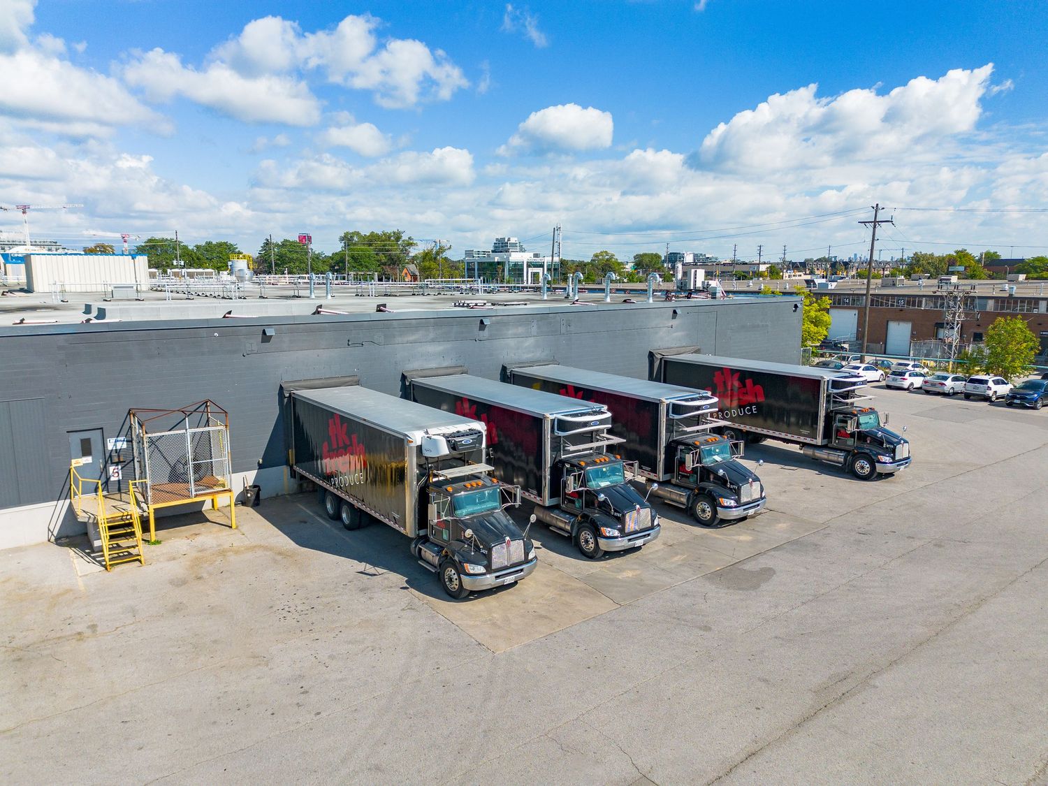 Panoramic view of a logistics facility parking lot with multiple loading docks and trucks.
