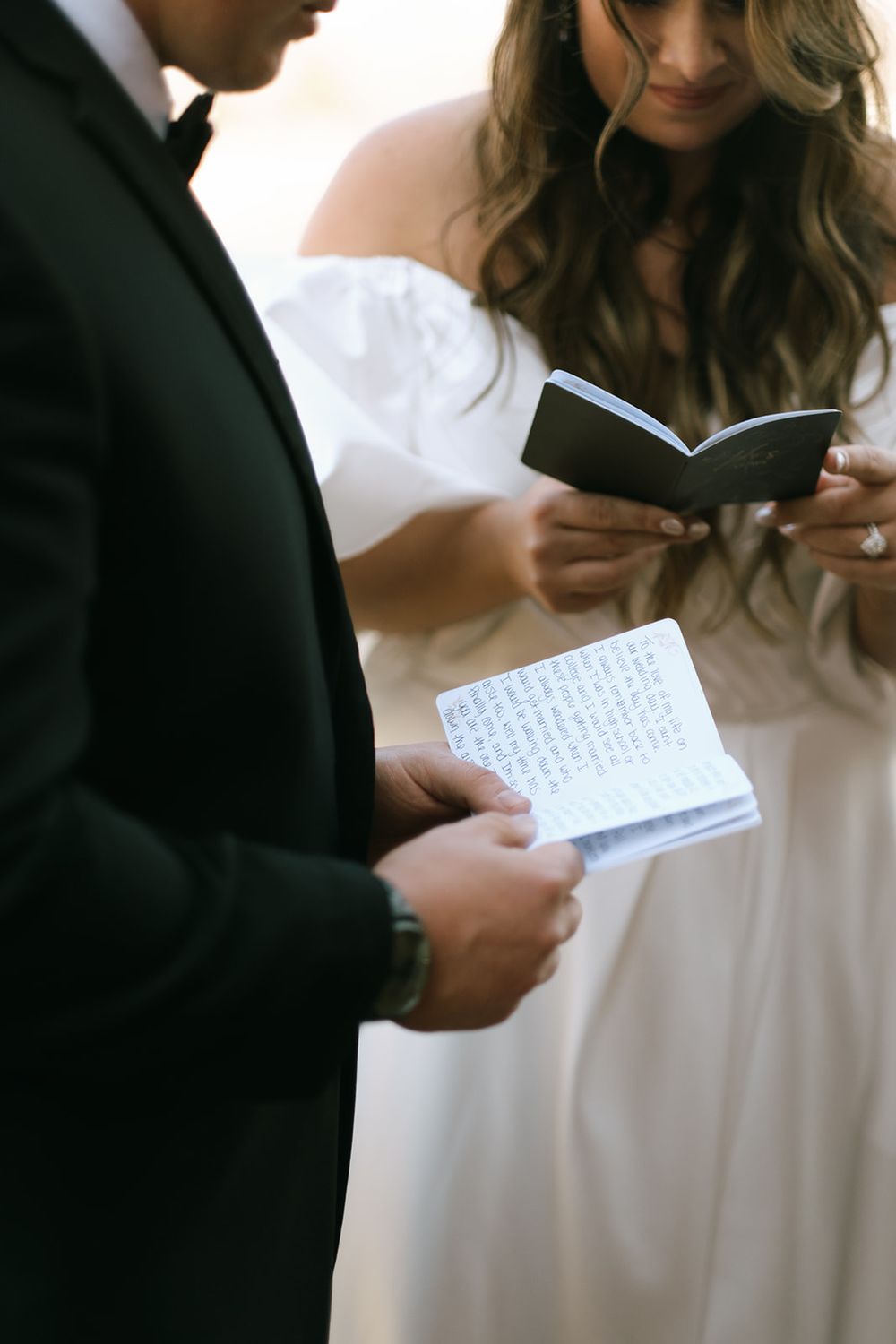 Bride and groom exchange handwritten personal vows during intimate outdoor wedding ceremony.