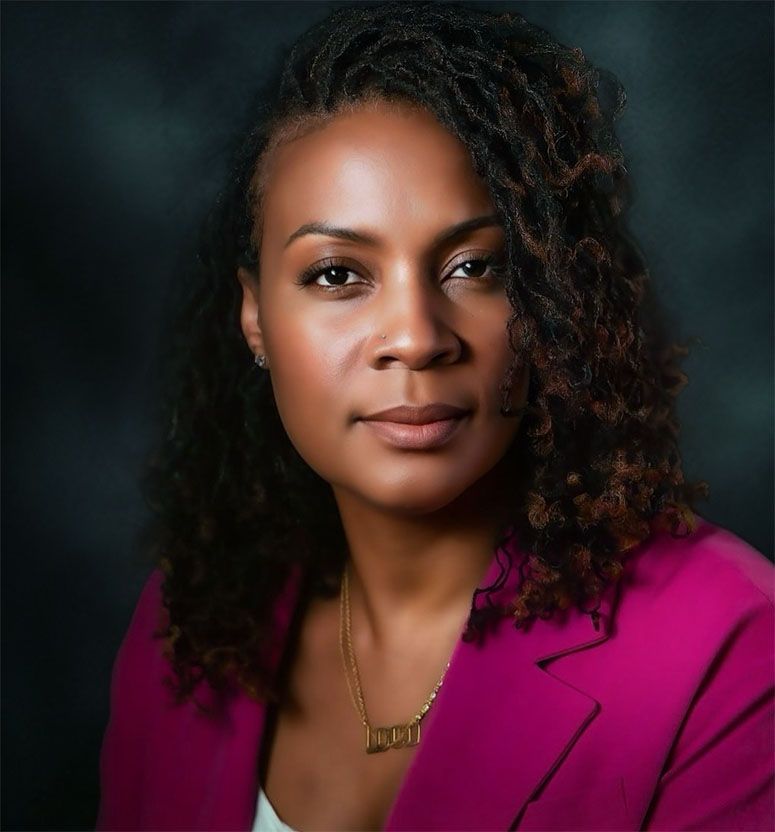 Professional portrait in magenta blazer against dark background.