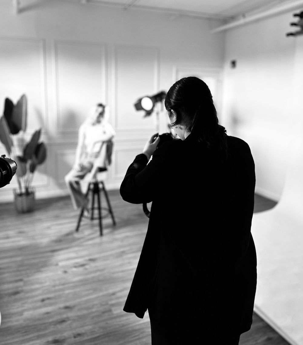 Silhouette of photographer working in studio with lighting equipment visible.