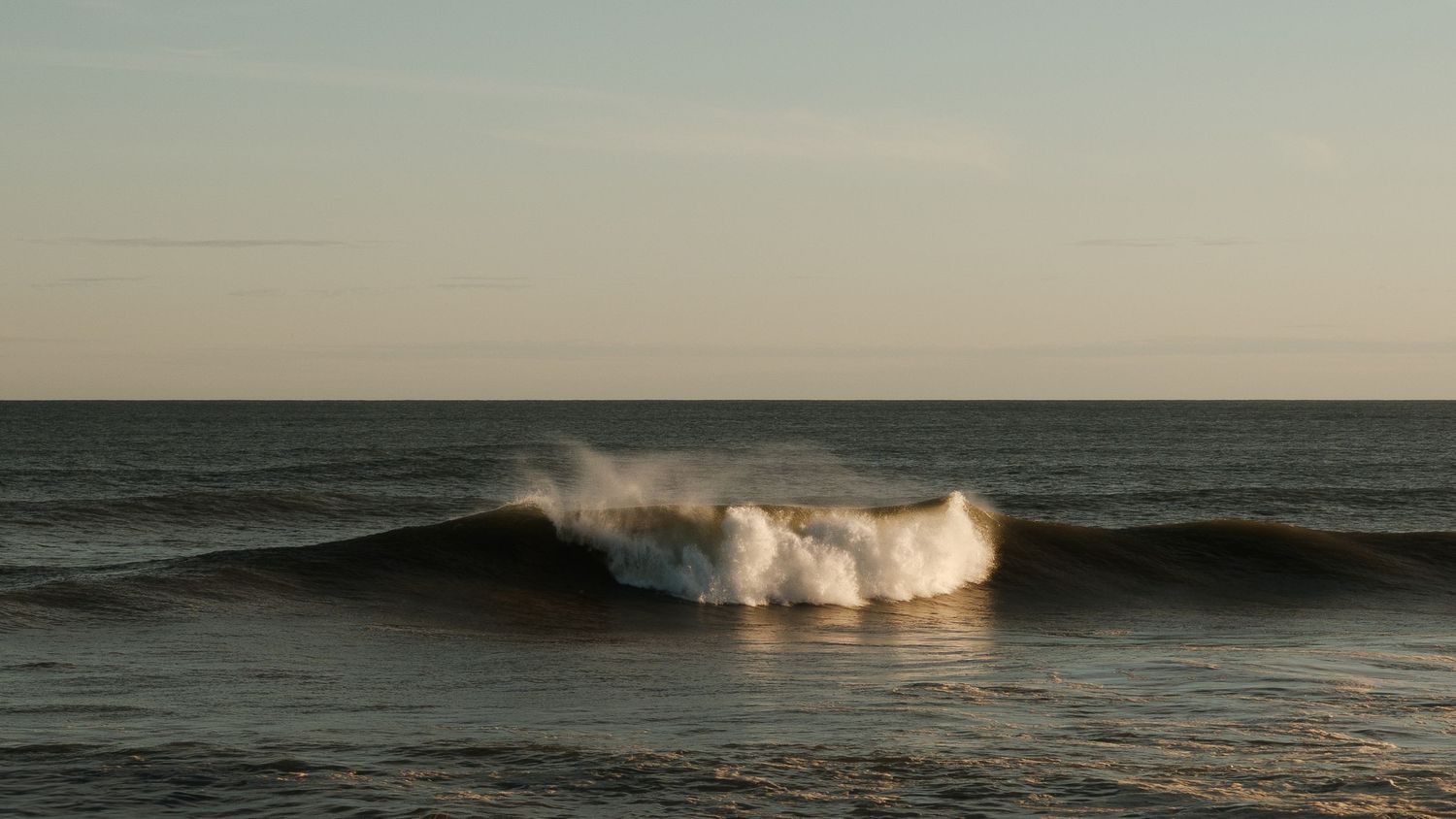 Ocean waves breaking at sunset with calm horizon view.