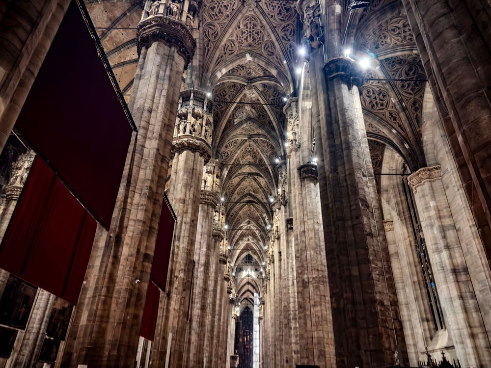 Gothic cathedral interior with towering stone columns and vaulted ceiling creating dramatic perspective.