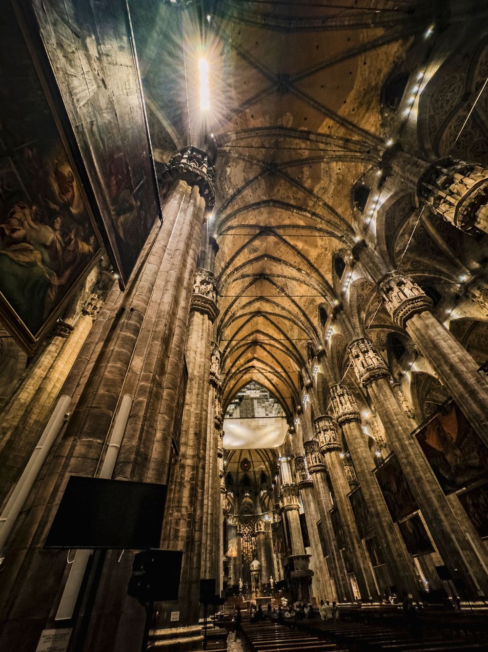 Cathedral interior with soaring vaulted ceiling and gothic columns illuminated by dramatic lighting.