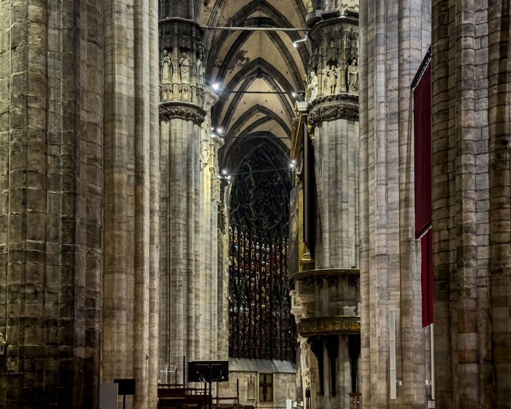 Gothic cathedral interior with soaring stone columns and vaulted ceilings creating dramatic architectural perspective.