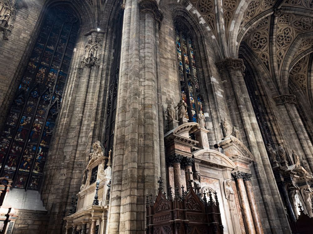 Gothic cathedral interior with soaring stone columns, ornate architectural details and dramatic lighting.