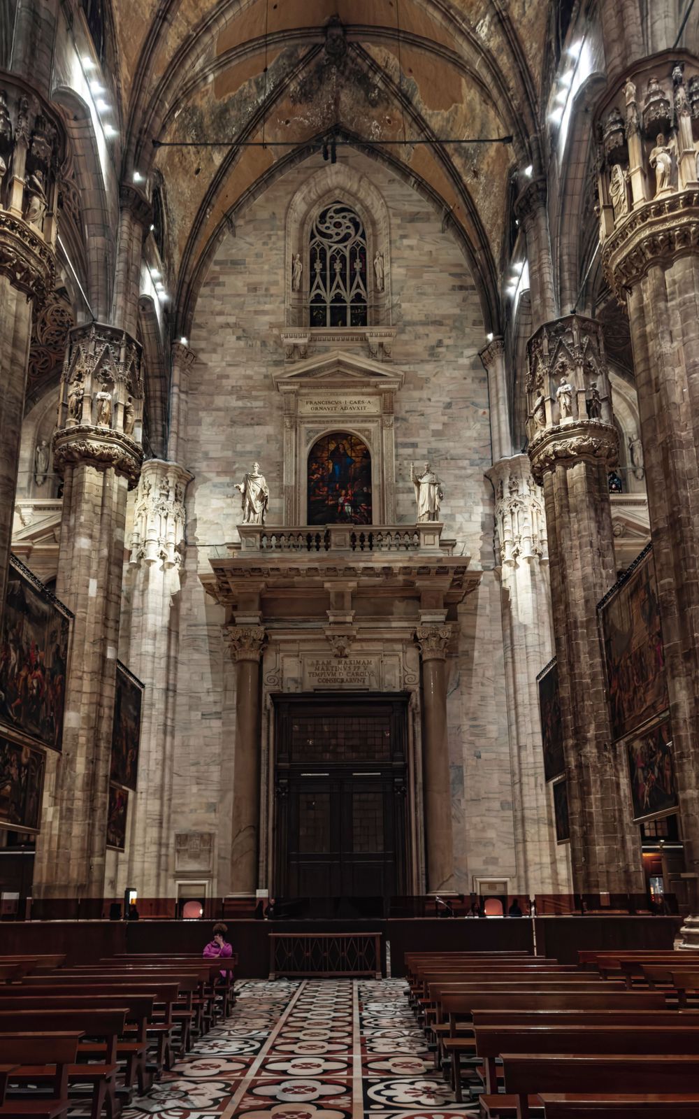 Majestic cathedral nave with vaulted ceilings, wooden pews and ornate stone carvings.