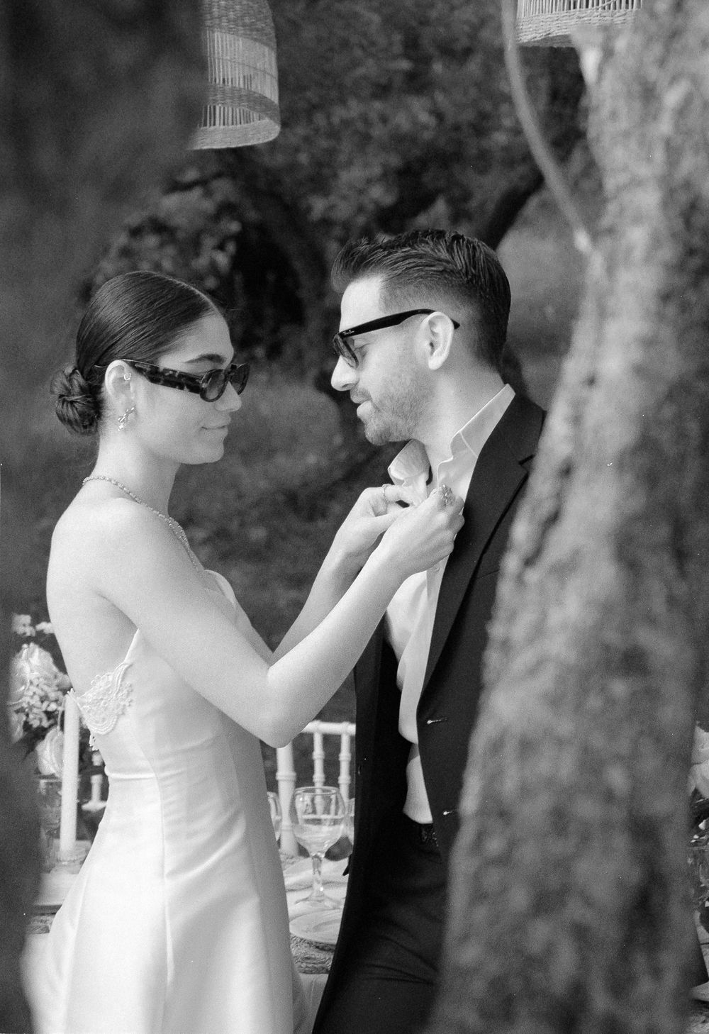 Bride adjusting groom’s shirt collar in a candid outdoor wedding moment